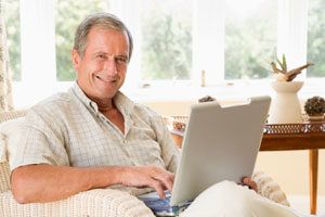 An elderly lady sitting with her laptop open.