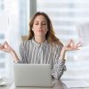 Calm female in office meditating to relieve the effects of stress.