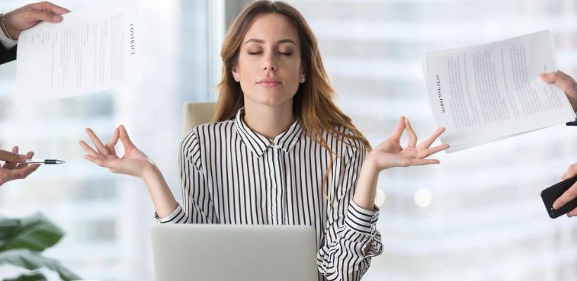 Calm female in office meditating to relieve the effects of stress.