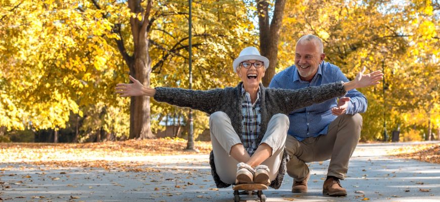 Elderly couple with a woman sitting on skate in the park